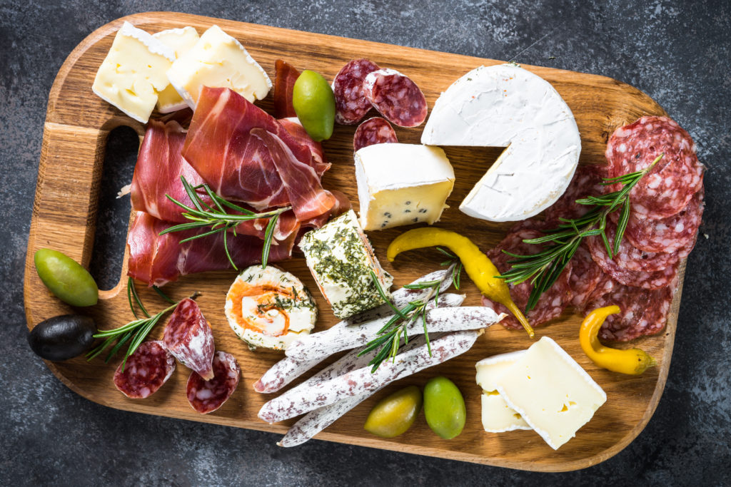 Antipasto - sliced meat, ham, salami, cheese, olives on wooden board. Top view.