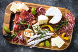 Antipasto - sliced meat, ham, salami, cheese, olives on wooden board. Top view.