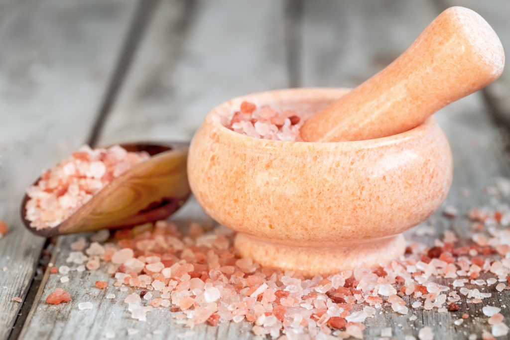 Pink himalayan salt in wooden scoop and rose quarz mortare on old wooden background