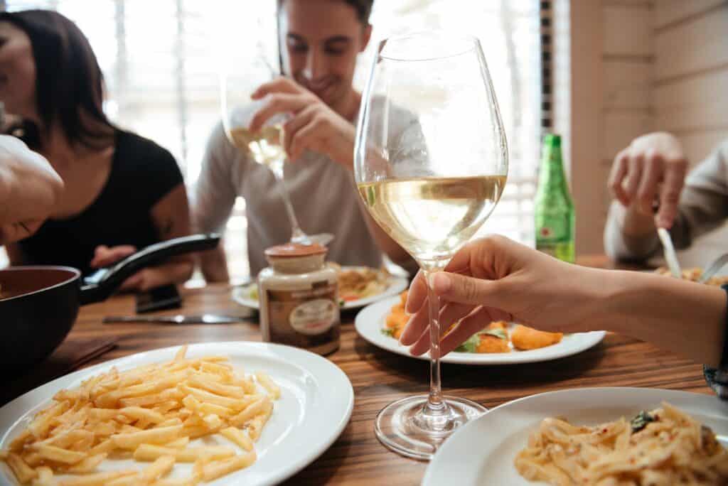 Closeup of people drinking wine and eating pasta at table