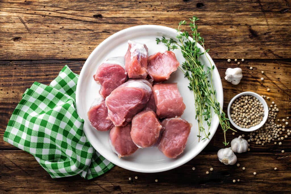 Fresh raw pork tenderloin, chopped meat on dark wooden rustic background, top view