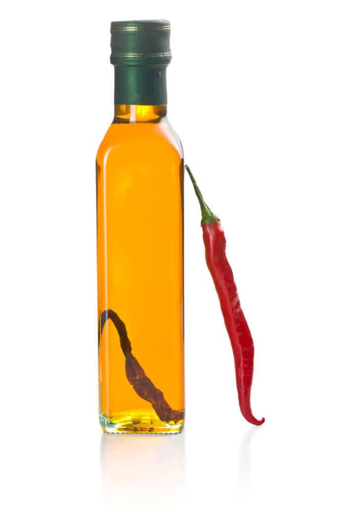 olive oil with chili peppers on white background